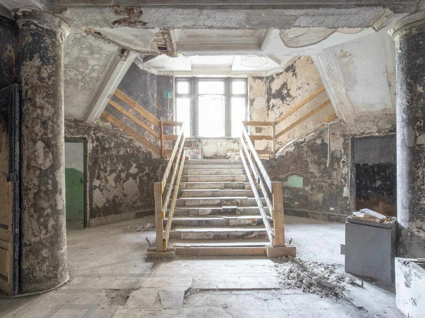 Историческое парадное пространство до восстановительных работ: облупленные стены, колонны, каменная лестница, временные деревянные перила